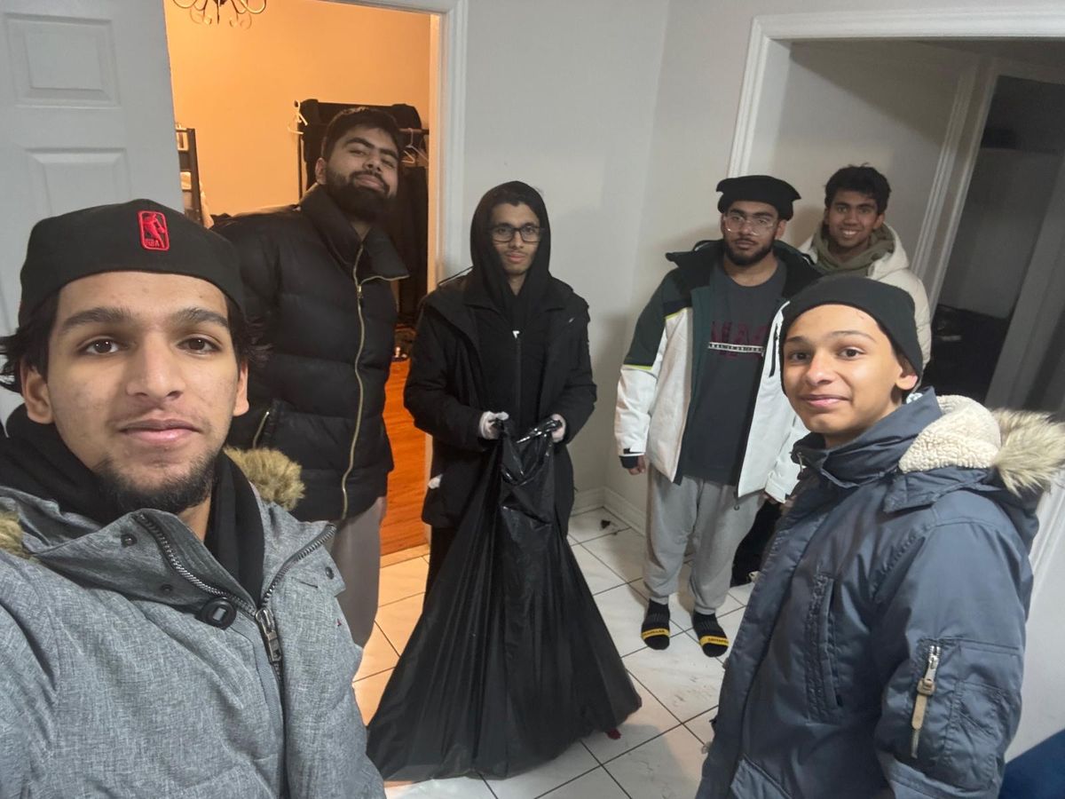 Six of us in winter coats indoors, gloves and collection bags in hand, about to head out.