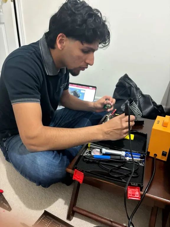 Soldering at a low table with a soldering station and tool case open.