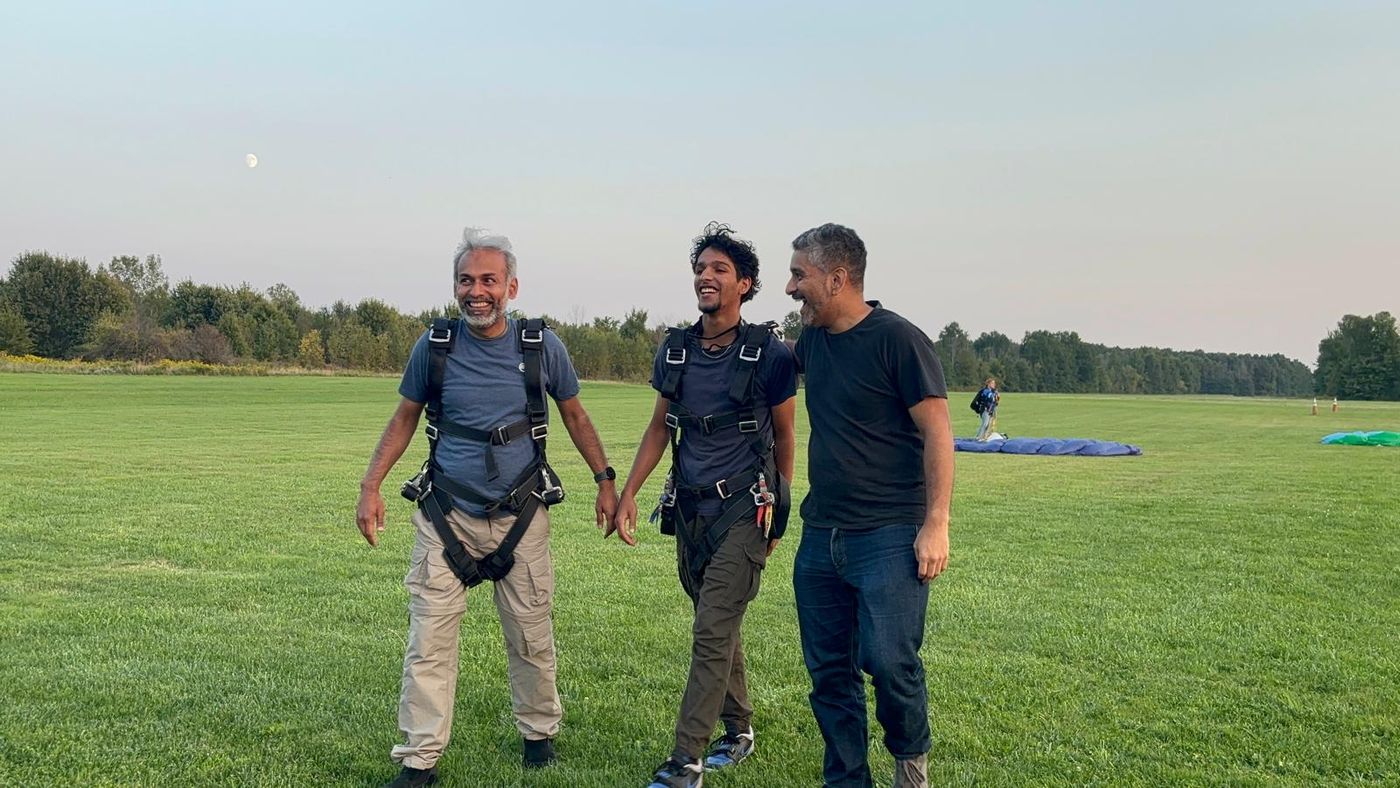Walking back across the landing field in a harness with the instructors, canopy on the grass behind.